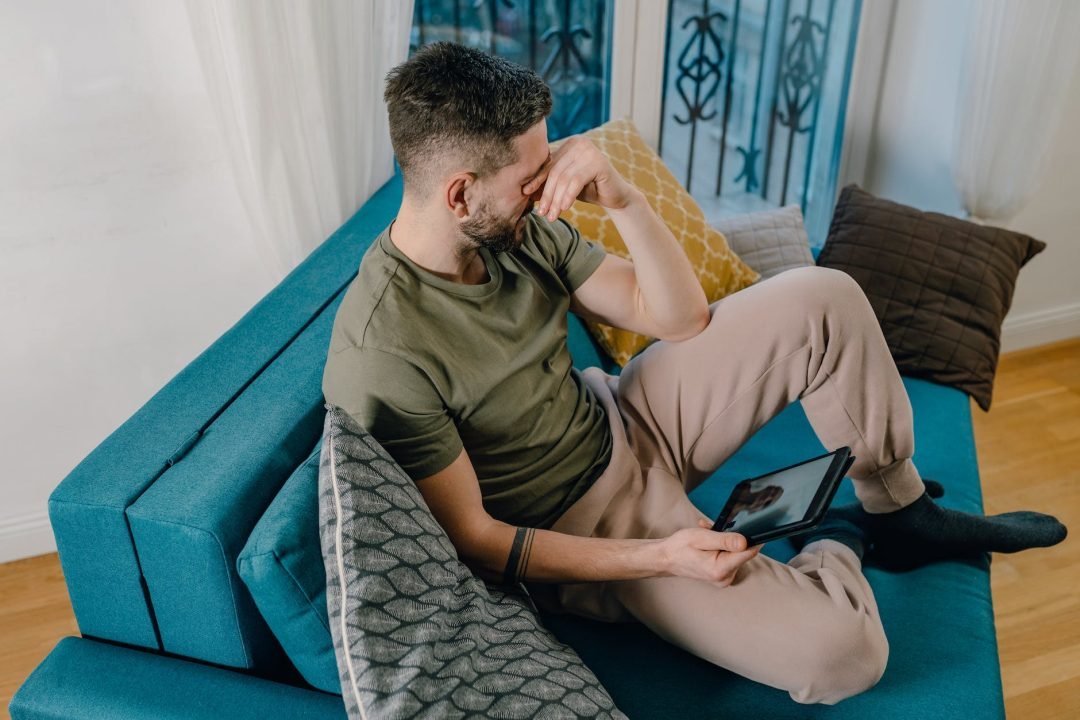photo of a man crying while sitting on a blue sofa