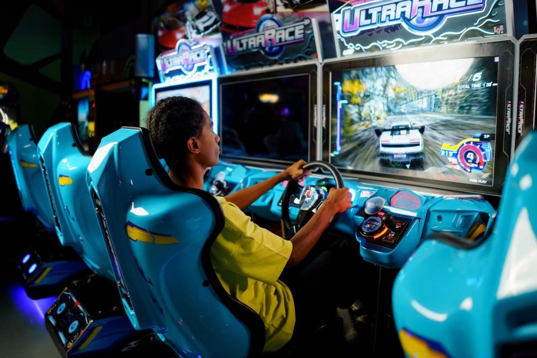 man in yellow shirt playing car arcade machine